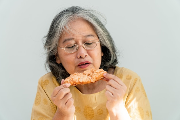 パイを食べることを楽しんで幸せなアジアの年配の女性