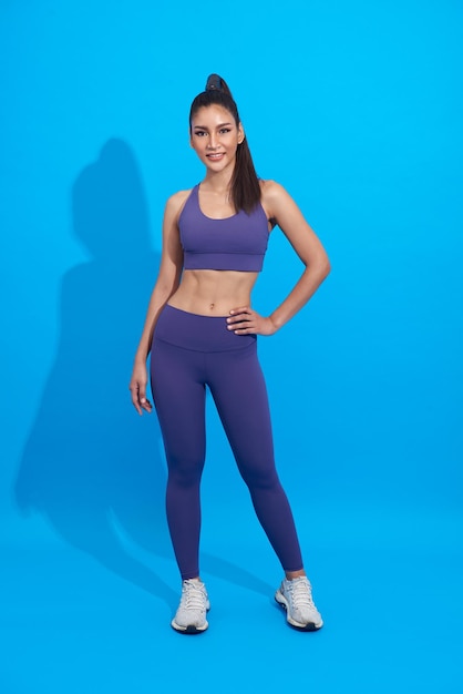 Happy asian sporty woman doing sport wearing sportswear over blue background