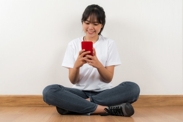 Happy asian student sitting with using phone at home background