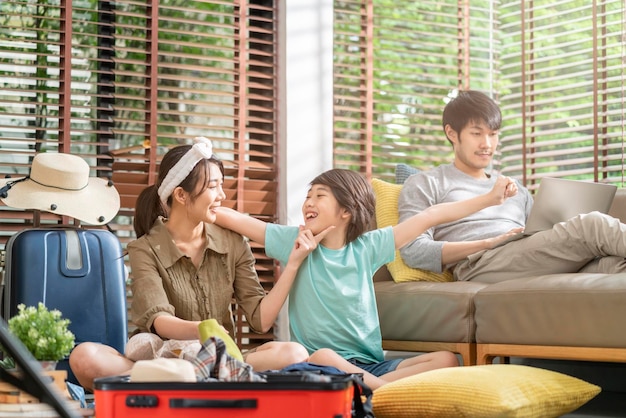 Happy asian sweet family prepare travel exited asian family
prepare packing cloth with suitcase luggage travel stuffs for
family holiday vacation together at living room at homehappy travel
together