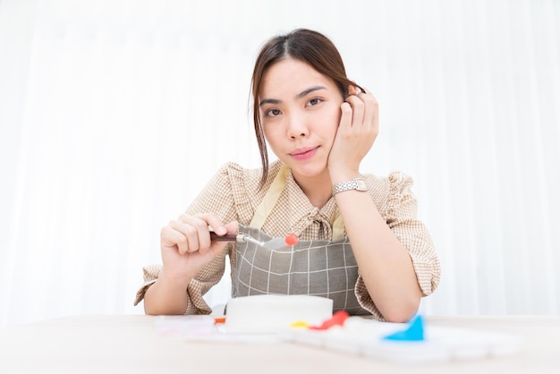 写真 幸せなアジア人女性シェフ甘いデザートケーキを作るベーカリーを焼く ベーカリーからキッチンレストランへ