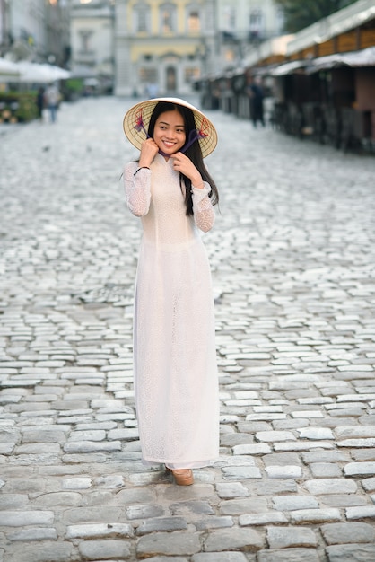 베트남어 원뿔 모자 비 라, 잎 모자와 전통적인 아오자이 하얀 드레스를 입고 행복 한 아시아 여자.