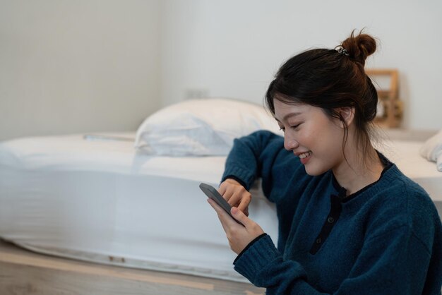 Happy asian woman hand using smartphone typing chatting conversation in chat box on her bedroom Social media maketing concept