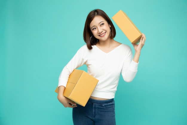 パッケージ宅配ボックス、配達宅配便および出荷サービスのコンセプトを保持している幸せなアジアの女性