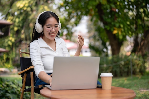 A happy Asian woman is having an online meeting working outdoors at her backyard garden