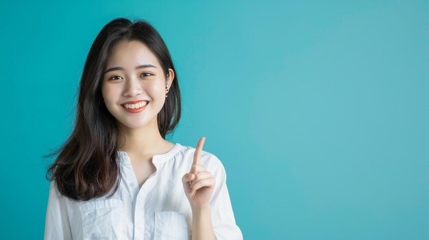 Foto una donna asiatica felice sorride e indica lo spazio di copia accanto a lei sullo sfondo blu