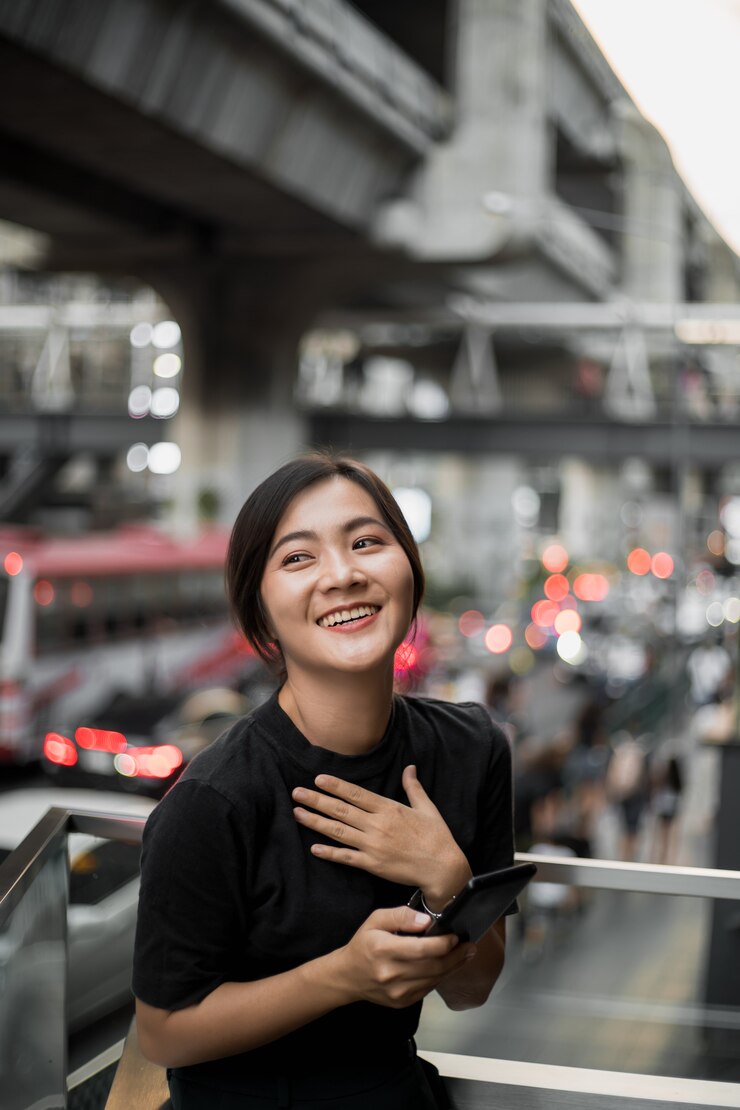 Photo 幸福的亞洲女人在城市裡看她的手機