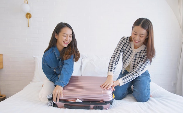 Happy asian woman packing suitcase on bed in room TravelerpeopleTourism and holiday concept