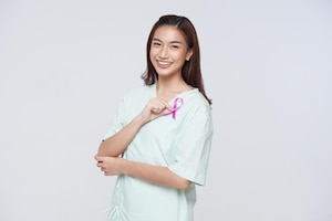 Happy asian woman patient showing pink badge ribbon chest to support breast cancer cause