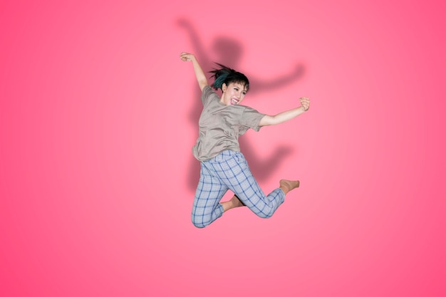 행복한 아시아 여성이 스튜디오에서 점프를 하고 있습니다.