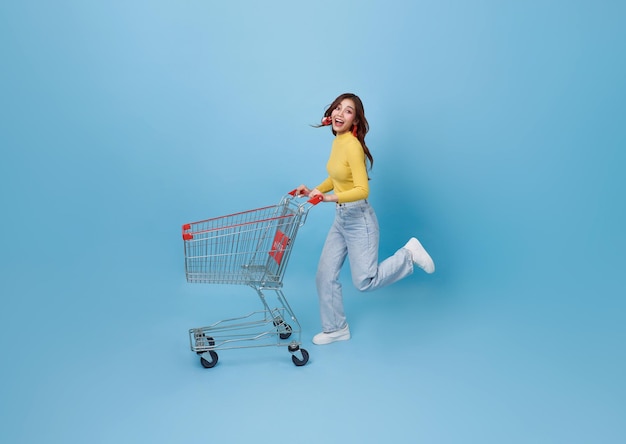 happy Asian woman pushing empty shopping cart or shopping trolley running promotion supermarket