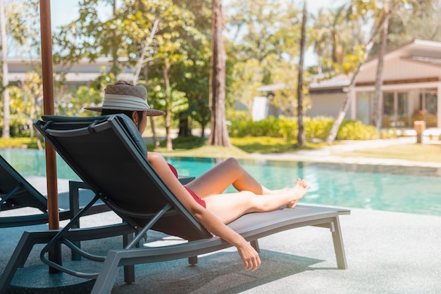 Happy asian woman in red swimsuit and a straw hat relaxing on chair beach at Phangnga Thailand