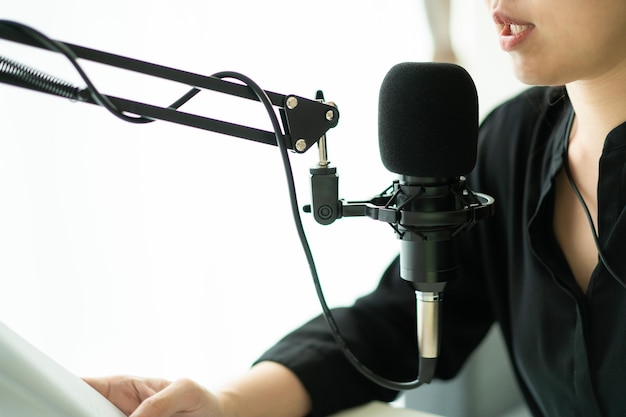 Happy asian woman setting up a living room in her house for\
podcast studio woman arranging a podcast and online radio station\
at home professional young podcaster speaking through a\
microphone