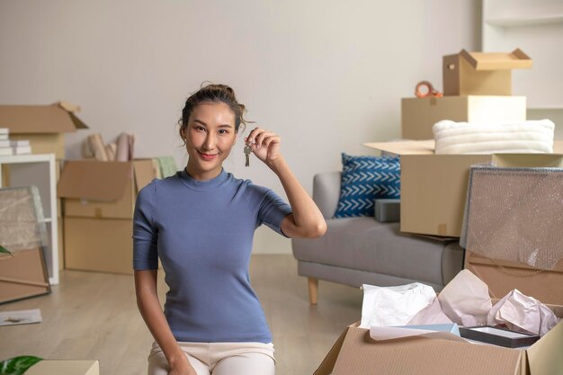 Photo happy asian woman showing keys in new house smiling and looking at camera