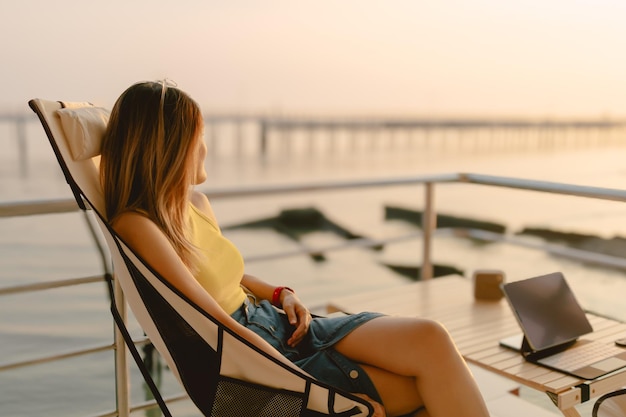 Happy asian woman sits and relaxed enjoy the sunset sea view of her honeymoon