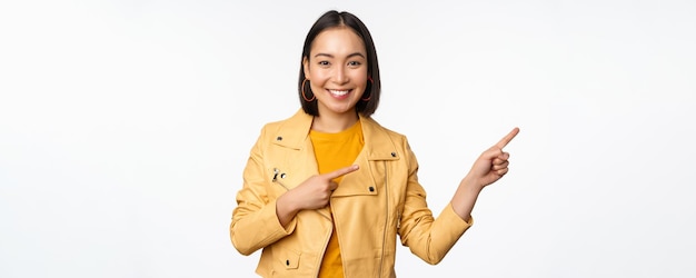 Happy asian woman smiling pointing fingers right inviting to check out sale showing advertisement ba