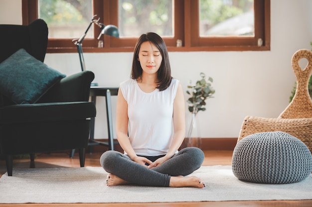 Happy Asian woman sporty attractive practicing meditation at home