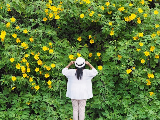 트리 메리 골드 또는 맥시 칸 해바라기 배경 위에 서 행복 아시아 여자.