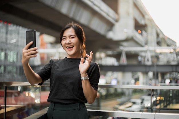 Happy asian woman taking a selfie in the city