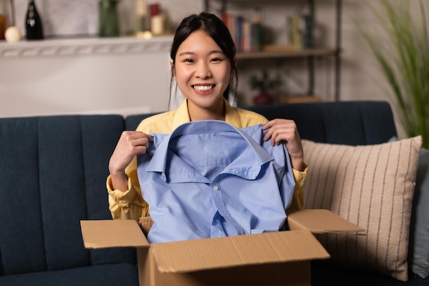 Happy asian woman unpacking parcel after online shopping