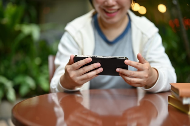 A happy Asian woman using her smartphone while relaxing at a table in her backyard