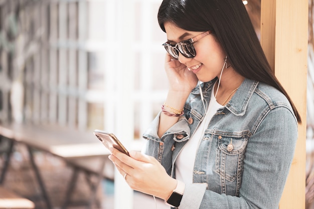 Happy Asian woman using phone for listening a music.