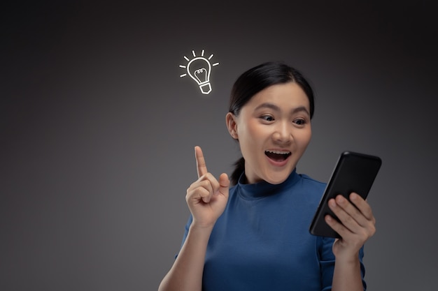 Happy Asian woman using smart phone and icon hologram effect