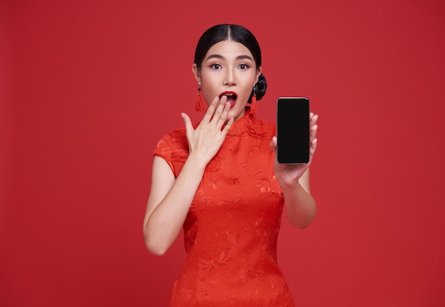 Happy Asian woman wearing traditional cheongsam qipao dress showing mobile phone