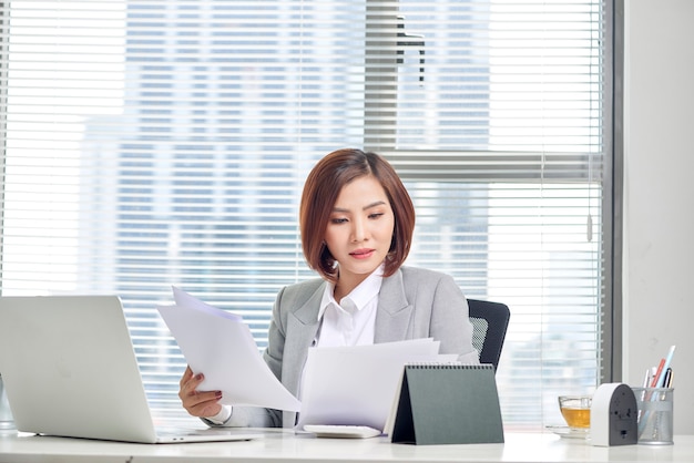 Photo happy asian woman working in office. female going through some paperwork at work place.