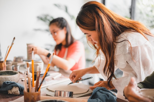 Happy asian woman working in pottery studio ceramic artist\
makes classes of hand building in modern pottery workshop creative\
people handcrafted design