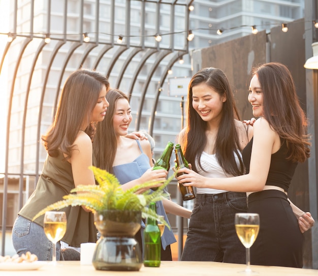 Happy asian women holding bottles of beer