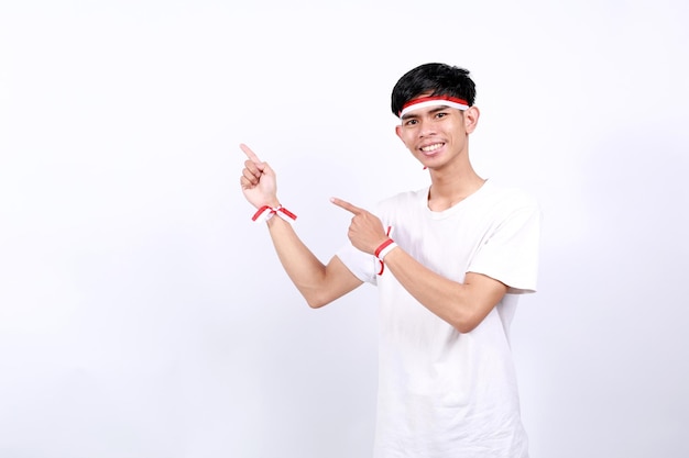 happy asian young boy with red white ribbon celebrating indonesia independence day while pointing sideways