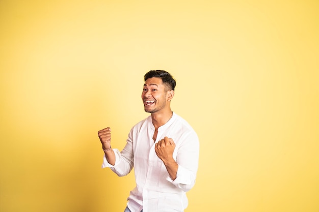 Happy asian young man with two hands clenched