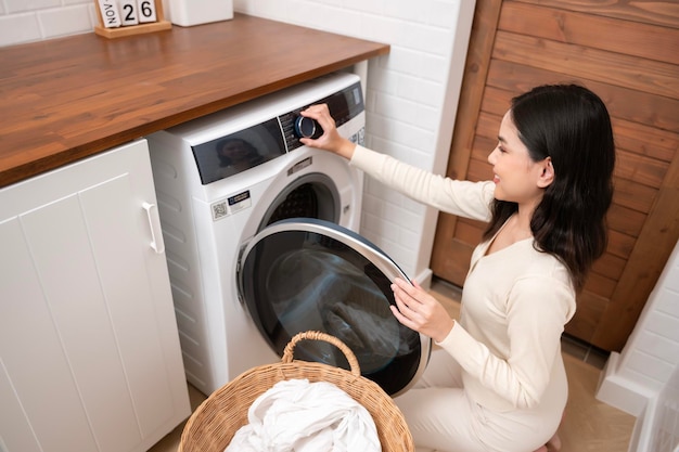 Happy Asian young woman is doing laundry in home healthy lifestyle concept