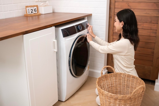 Happy Asian young woman is doing laundry in home healthy lifestyle concept