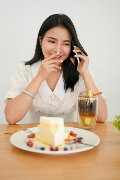 Happy Asian young woman waiting her friends in the cafe enjoy talking on the phone with someone