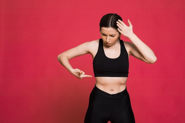 Happy athletic woman Photo of sporty woman in fashionable black sportswear on red background