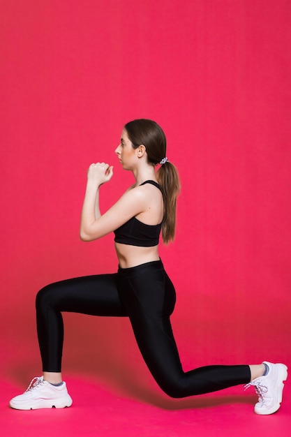 Happy athletic woman Photo of sporty woman in fashionable black sportswear on red background