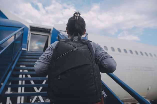 Photo happy attractive asian woman traveler with backpack at the modern airport terminal copy space tourist journey trip concept