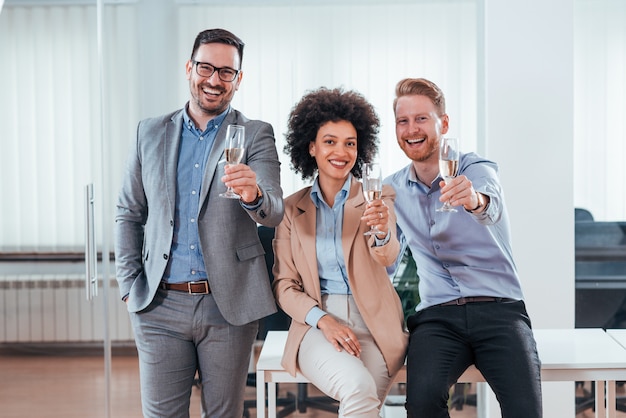 Happy attractive business people holding glass of champagne.