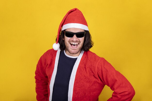 Happy and attractive man is dressed as santa claus he is wearing sunglasses and a red hat