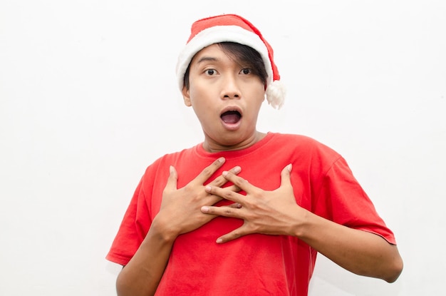 幸せな魅力的なショックを受けたアジア人の男は、白で隔離された赤いクリスマス テーマの服を着ています。