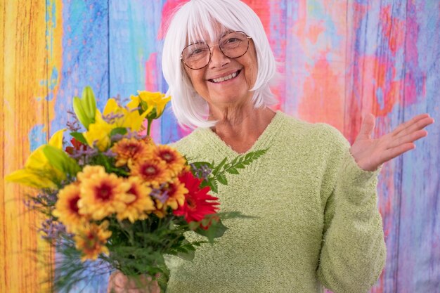 Foto felice attraente donna anziana dai capelli bianchi che riceve un mazzo di fiori festa di compleanno per la festa della donna di san valentino