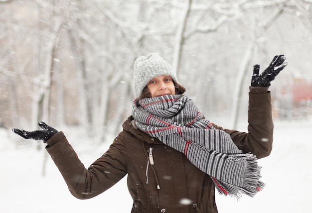 Felice donna attraente in abiti caldi in inverno tempo nevoso all'aperto