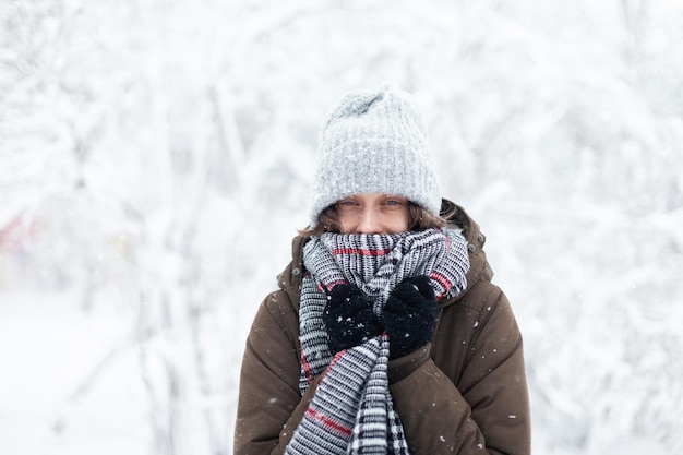 冬の雪の屋外で暖かい服装で幸せな魅力的な女性