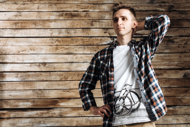 Happy attractive young man in plaid shirt standing and smiling\
over wooden background