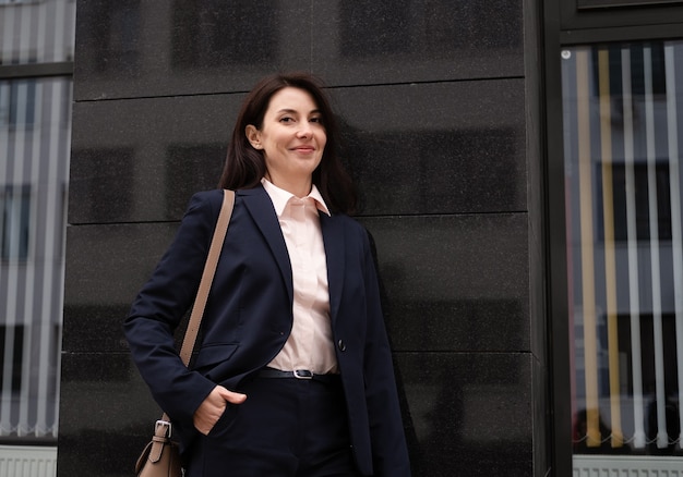 Felice giovane donna attraente in autunno all'aperto. la donna di affari va per un lavoro. avvicinamento.