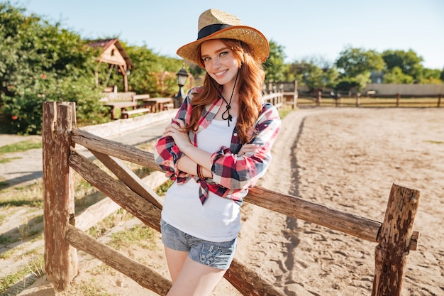 Happy attractive young woman cowgirl standing with hands folded