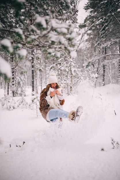 Happy attractive young woman kicking snow snowy winter forest