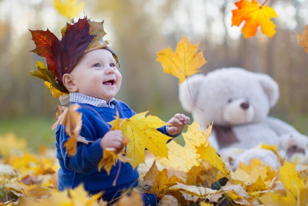 Happy baby in autumn park plays with leaves